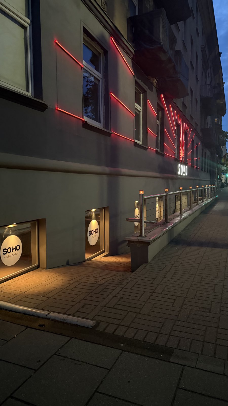 Soho's red-neon facade and entrance on Švitrigailos g., Vilnius, at dusk